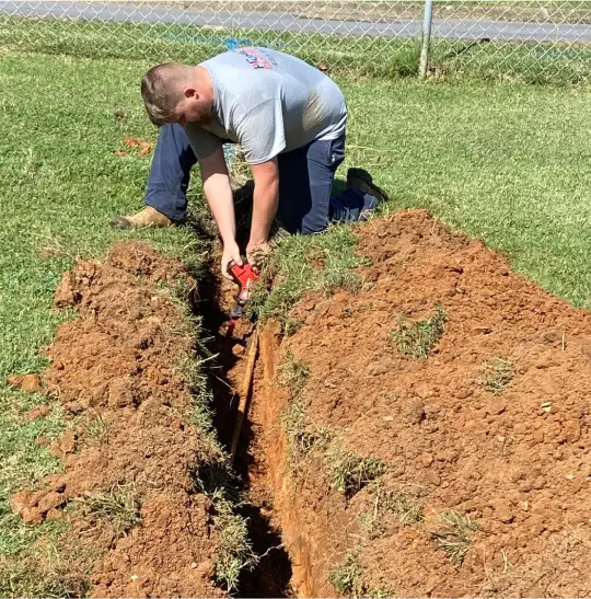 plumbing technician digging in yard to work on waterline