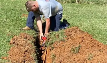 plumbing technician digging in yard to work on waterline