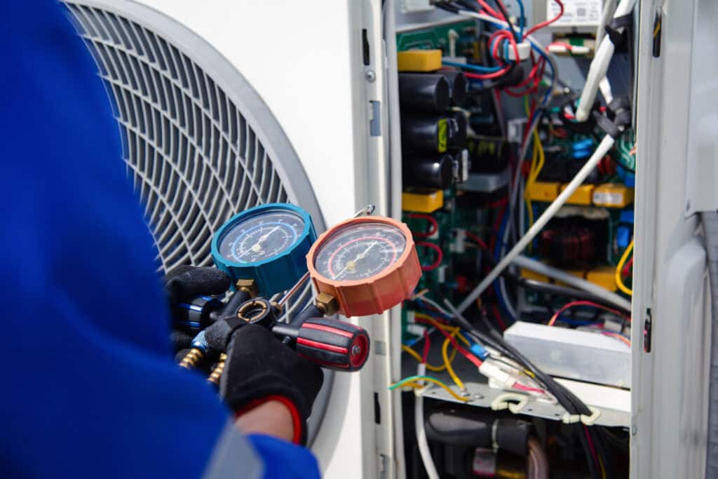 Close view of a technician's hands holding tools as he installs a new heat pump.